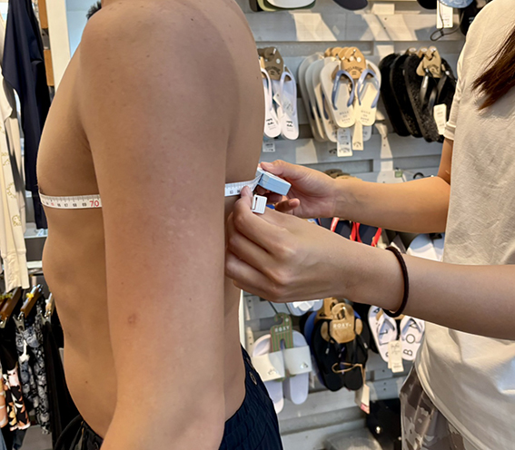 男性がメジャーで胸囲を採寸してもらっている様子
