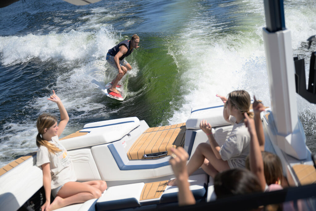 ウェイクサーフィンをしている男性とボートから見ている二人